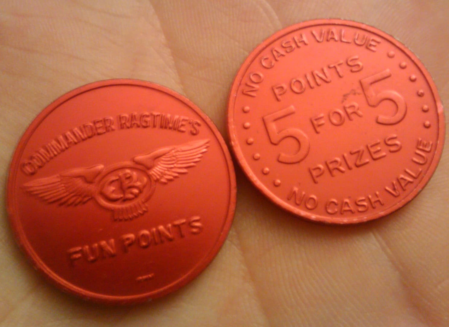 Two orange arcade point tokens stamped “No cash value”